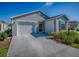 Well-maintained single-story home with a two-car garage and a concrete driveway, set under a clear blue sky at 865 Conroe St, The Villages, FL 34762