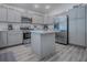 Bright kitchen boasts stainless steel appliances, gray cabinets, a convenient island, and modern flooring at 865 Conroe St, The Villages, FL 34762