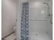 Modern bathroom walk-in shower featuring white subway tiles and a stylish blue floral shower curtain and toilet at 865 Conroe St, The Villages, FL 34762