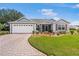 Charming single-story home featuring a manicured lawn, brick driveway, and attached two-car garage at 8980 Se 176Th Limerick Ln, The Villages, FL 32162
