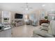 Bright living room featuring tile floors, a ceiling fan, comfortable seating, and a large television at 8980 Se 176Th Limerick Ln, The Villages, FL 32162