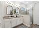 Modern bathroom featuring dual sinks, white cabinetry, decorative mirrors and a tiled shower with glass enclosure at 9307 San Jose Blvd, Howey In The Hills, FL 34737
