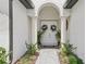 Elegant front entry with double doors, adorned with wreaths, flanked by columns and manicured landscaping at 9307 San Jose Blvd, Howey In The Hills, FL 34737
