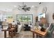 Bright living room with white sofas, wood floors, ceiling fan, and a view of a landscaped backyard at 9307 San Jose Blvd, Howey In The Hills, FL 34737
