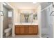 Bathroom featuring double sink vanity with granite counters and a shower with glass doors at 997 Nash Loop, The Villages, FL 32162