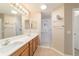 Bathroom featuring double sink vanity with granite counters and shower with glass doors at 997 Nash Loop, The Villages, FL 32162