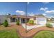 A beautiful home with light brown siding, manicured lawn, mulch beds, and concrete walkway at 997 Nash Loop, The Villages, FL 32162