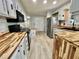 Kitchen featuring butcher block countertops, stainless steel refrigerator, and white cabinets at 105 Temple W Cv, Leesburg, FL 34748