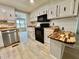 Bright kitchen features white cabinetry, black appliances, and butcher block countertops at 105 Temple W Cv, Leesburg, FL 34748