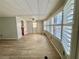 Living room with neutral walls, wood-look flooring, and large windows with blinds at 105 Temple W Cv, Leesburg, FL 34748