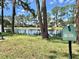 Picturesque pond view featuring a lush grassy bank, towering trees, and charming homes in the background at 105 Temple W Cv, Leesburg, FL 34748