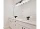 Bright bathroom featuring a double vanity with white countertop, black hardware, and a large framed mirror at 1191 Stratton Ave, Groveland, FL 34736