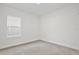 Bedroom with neutral carpet, baseboards, white walls, and a single window at 1191 Stratton Ave, Groveland, FL 34736