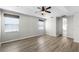 Main bedroom features wood floors, a ceiling fan, and two windows, creating a tranquil and airy space at 12838 Owasso Ln, Clermont, FL 34711