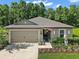 Charming home featuring manicured landscaping, two-car garage, and a welcoming entrance with tasteful decorative elements at 12952 Del Lago Dr, Astatula, FL 34705