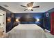 Cozy main bedroom with a dark blue accent wall, ceiling fan, and warm lighting at 12952 Del Lago Dr, Astatula, FL 34705