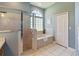 Bathroom with a walk-in shower, garden tub, tile flooring, and natural light from the window at 13100 Lakewind Dr, Clermont, FL 34711