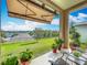 Covered patio featuring an awning, comfortable seating, and views of the lush green backyard at 1454 Westbury Dr, Clermont, FL 34711