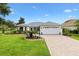 Charming single-story home with a well-manicured lawn, paver driveway, and a two-car garage at 1514 Vandam St, The Villages, FL 32162