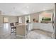 Modern kitchen island with bar seating, white cabinets, and marble-look tile flooring at 1514 Vandam St, The Villages, FL 32162