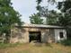 Weathered barn with worn wooden walls, open doors, surrounded by tall trees and plants at 15587 Se 150Th Ave, Weirsdale, FL 32195