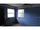 Bedroom showing worn blue walls, two windows, and ceiling fan, providing a blank canvas for complete transformation at 15587 Se 150Th Ave, Weirsdale, FL 32195
