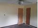 Bedroom with beige walls, two doors, and worn hardwood flooring at 15587 Se 150Th Ave, Weirsdale, FL 32195