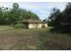 Exterior view of a single-story home with overgrown vegetation, offering renovation possibilities at 15587 Se 150Th Ave, Weirsdale, FL 32195
