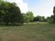 Open parcel of land, bordered by dense trees, powerlines, and distant vehicle in the background at 15587 Se 150Th Ave, Weirsdale, FL 32195