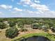 Aerial view of a serene property with a home, pool, and picturesque pond surrounded by lush greenery at 15837 Hidden Lake Cir, Clermont, FL 34711