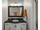 Nicely renovated bathroom features a dark vanity and a large framed mirror with a lighting fixture at 15837 Hidden Lake Cir, Clermont, FL 34711