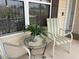 Cozy front porch sitting area with glass table, chairs, and view of lush greenery at 1723 Banberry Run, The Villages, FL 32162