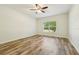 Bright bedroom with laminate flooring, a ceiling fan, and a window with a view of lush trees at 185 Hamlet Loop, Davenport, FL 33837