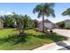 Well-maintained home showcasing lush green lawn, mature palm trees, and colorful landscaping beds at 1910 Quiet Oak Ct, The Villages, FL 32162