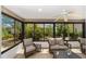 This sunroom is surrounded by windows and boasts a ceiling fan and comfortable seating at 1910 Quiet Oak Ct, The Villages, FL 32162
