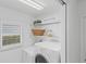 Bright laundry room with stacked washer and dryer, shelving, and a window at 1963 Ladyfish Ave, The Villages, FL 32162