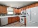 Well-lit kitchen featuring wood cabinets, white appliances, and a mosaic tile backsplash at 2050 Duval Ct, The Villages, FL 32162