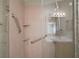 Close-up of a glass enclosed shower featuring tile walls, safety bars, and built-in shelves at 2050 Duval Ct, The Villages, FL 32162