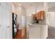 Well-lit kitchen features wooden cabinetry, hardwood floors, black appliances, and view to living area at 211 Highland Meadows Ct, Davenport, FL 33837
