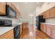 Well-lit kitchen features wooden cabinetry, hardwood floors, black appliances, and view to dining area at 211 Highland Meadows Ct, Davenport, FL 33837