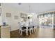 Bright dining room with white table and chairs, wood floors, and sliding door to the lanai at 2111 Thornton Ter, The Villages, FL 32162
