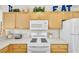 Bright kitchen with wooden cabinets, white appliances, and an eat sign at 2111 Thornton Ter, The Villages, FL 32162