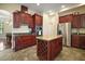 Kitchen featuring cherry cabinets, a granite island, stainless steel appliances, and a tiled floor at 21206 Canoe Pass St, Clermont, FL 34715