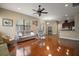 Open-concept living room features hardwood floors, neutral paint, and ceiling fan with a light fixture at 21206 Canoe Pass St, Clermont, FL 34715
