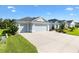 Street view of a single Gathering home with a three car garage, concrete driveway and mature landscaping at 2321 Demarco Dr, The Villages, FL 32163