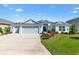 Charming single Gathering home featuring a three car garage, mature landscaping and a covered entryway at 2321 Demarco Dr, The Villages, FL 32163
