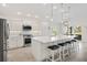 This kitchen boasts white cabinetry, stone countertops, stainless appliances, and an island with pendant lights at 2321 Demarco Dr, The Villages, FL 32163
