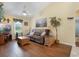 Comfortable living room with hardwood floors, a ceiling fan, a large sofa, and natural light at 25236 Waterbridge Ct, Leesburg, FL 34748