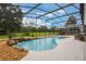 Screened-in pool area with waterfall feature and well-manicured lawn at 25236 Waterbridge Ct, Leesburg, FL 34748