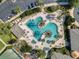 Aerial view of the pool and community area featuring mature palm trees, lounge chairs, and a tennis court at 27018 Nature View St, Leesburg, FL 34748